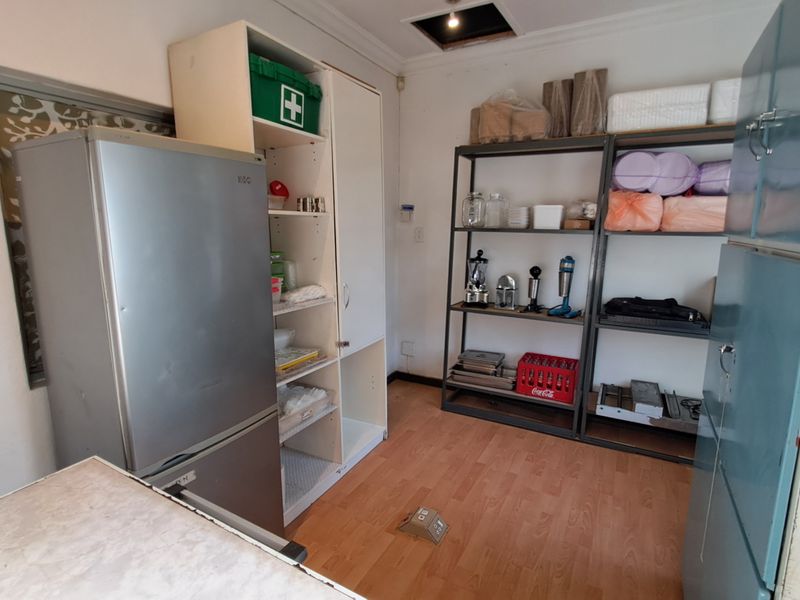 A functional scullery or utility storage area featuring built-in cabinetry and laminate flooring, suitable for additional kitchen prep or storage needs.