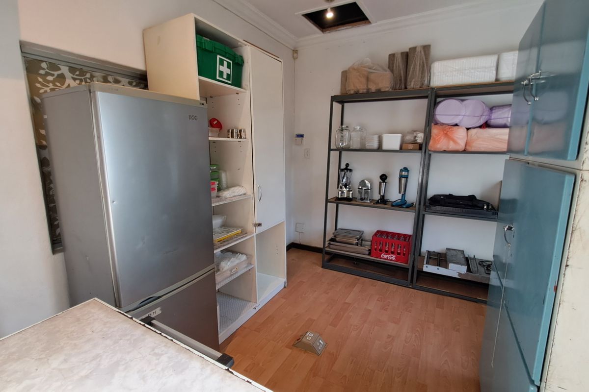 A functional scullery or utility storage area featuring built-in cabinetry and laminate flooring, suitable for additional kitchen prep or storage needs.