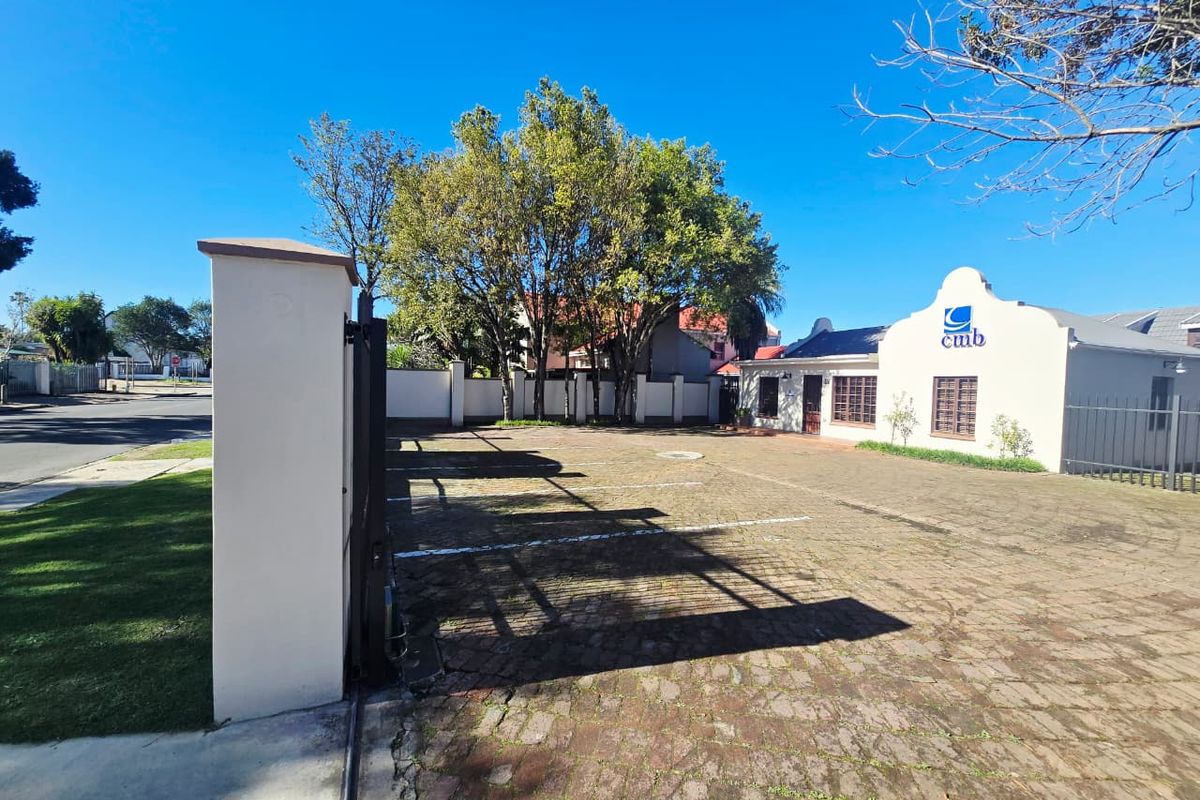 Front exterior view of the office property featuring a paved parking area, secure boundary wall, and gated entrance.