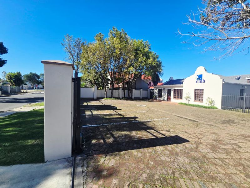 Front exterior view of the office property featuring a paved parking area, secure boundary wall, and gated entrance.