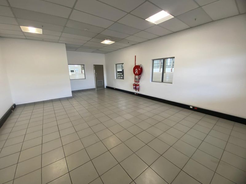 A clean, open-plan industrial utility space featuring tiled flooring, a suspended ceiling with recessed lighting, and integrated fire safety equipment.