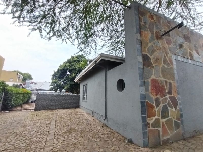 Rear exterior view of the property featuring stone cladding, a circular window, and cobblestone paving in the courtyard area.