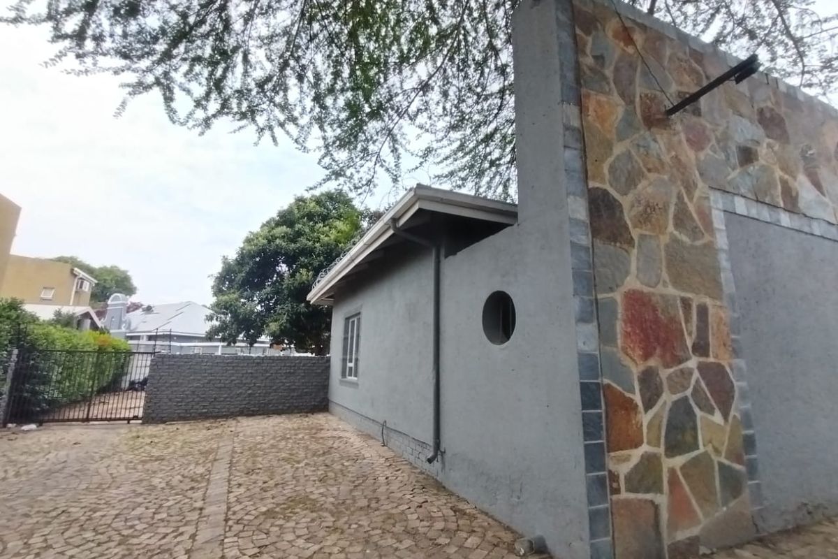 Rear exterior view of the property featuring stone cladding, a circular window, and cobblestone paving in the courtyard area.