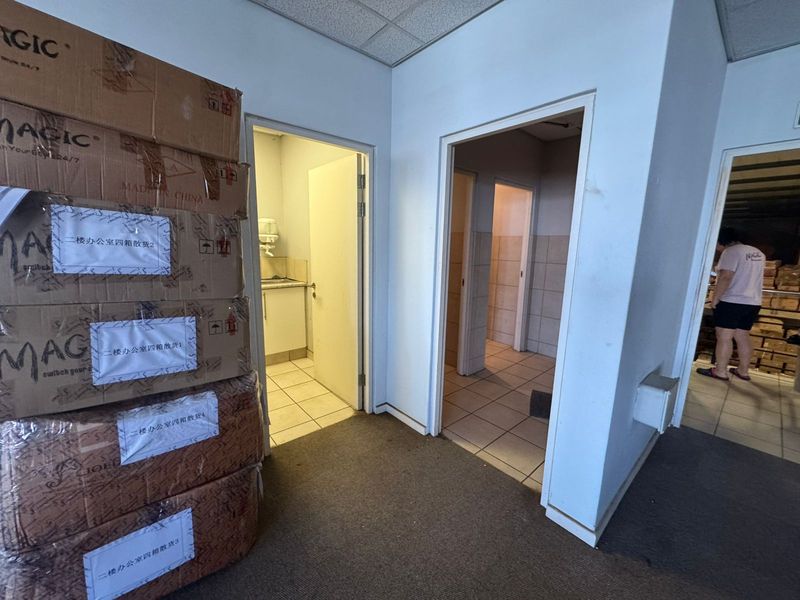 A functional industrial hallway providing access to multiple utility and office spaces, featuring tiled flooring and standard internal door frames.