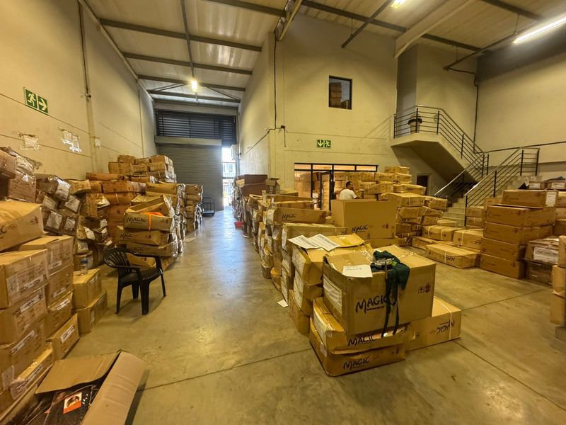 Spacious industrial warehouse unit featuring high ceilings with exposed steel trusses, concrete flooring, and an internal metal staircase for mezzanine access.