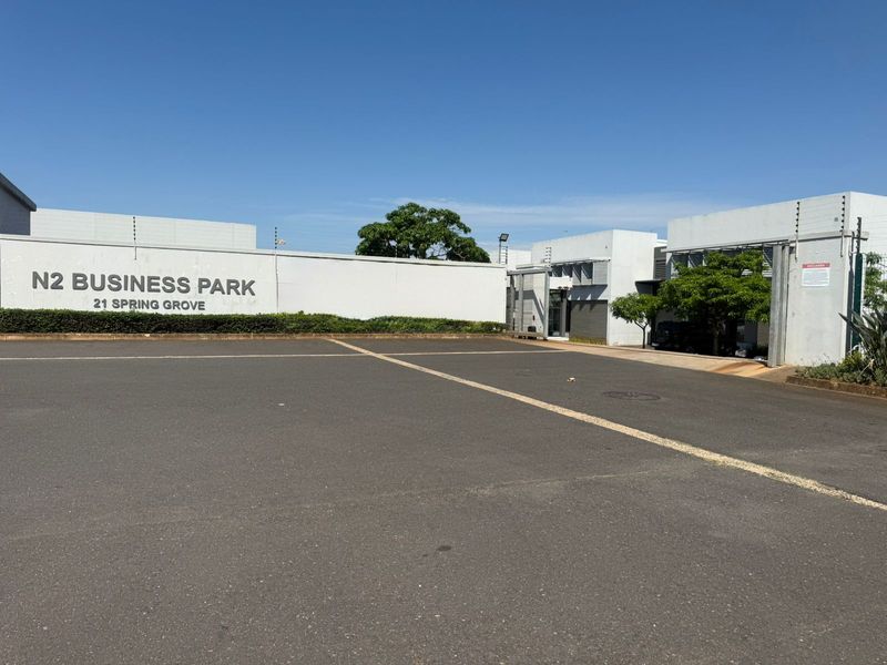Front exterior view of N2 Business Park featuring a paved parking area, perimeter wall with electric fencing, and clear business signage.