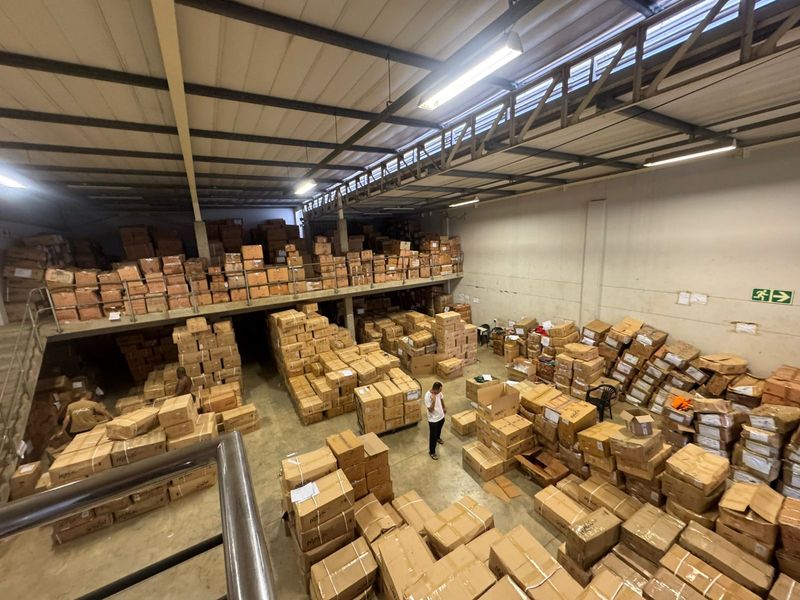 Spacious industrial warehouse featuring a mezzanine level, exposed steel roof trusses, and concrete flooring, currently utilized for bulk storage.