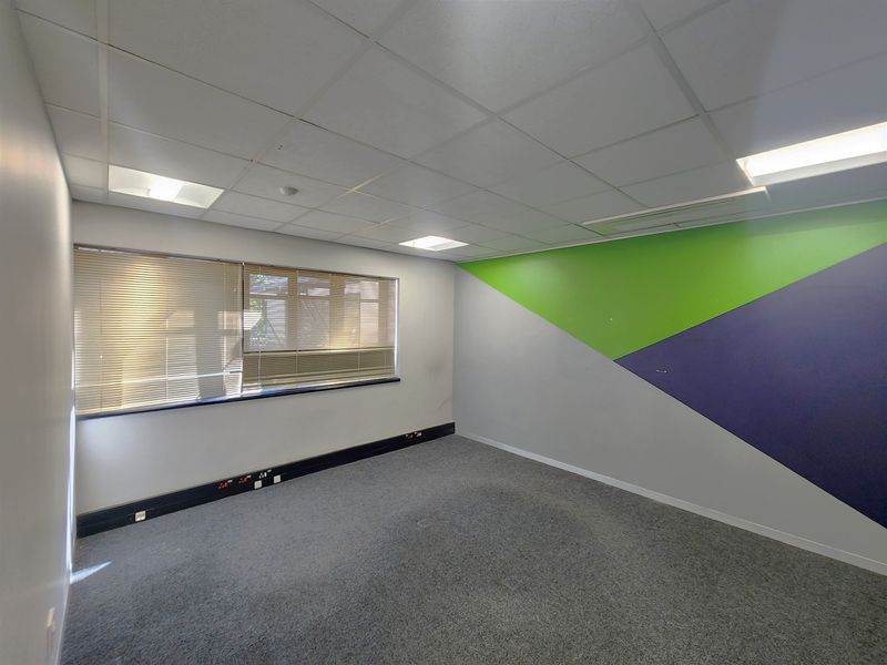 A clean, empty office space featuring a suspended ceiling, recessed lighting, carpeted flooring, and integrated skirting trunking for electrical and data connectivity.