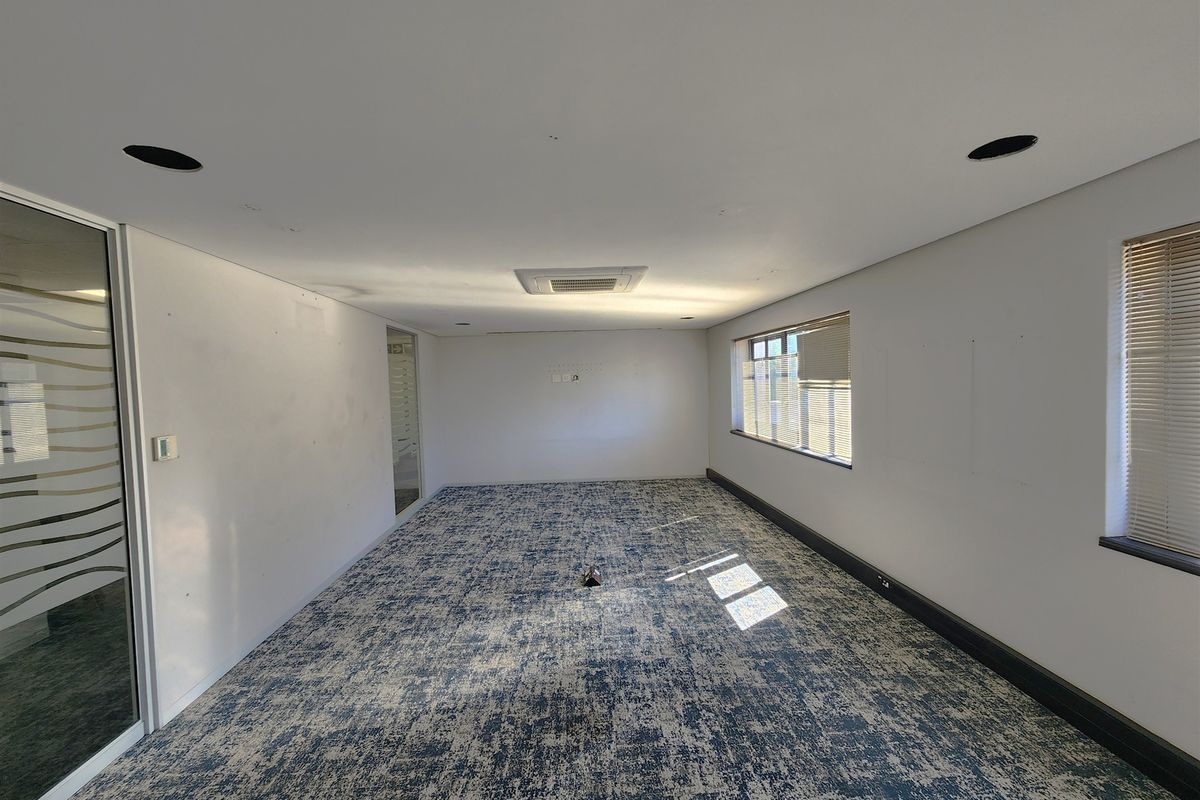 A vacant office space featuring patterned carpeting, recessed ceiling lighting, ducted air conditioning, and a glass partition wall with natural light from side windows.