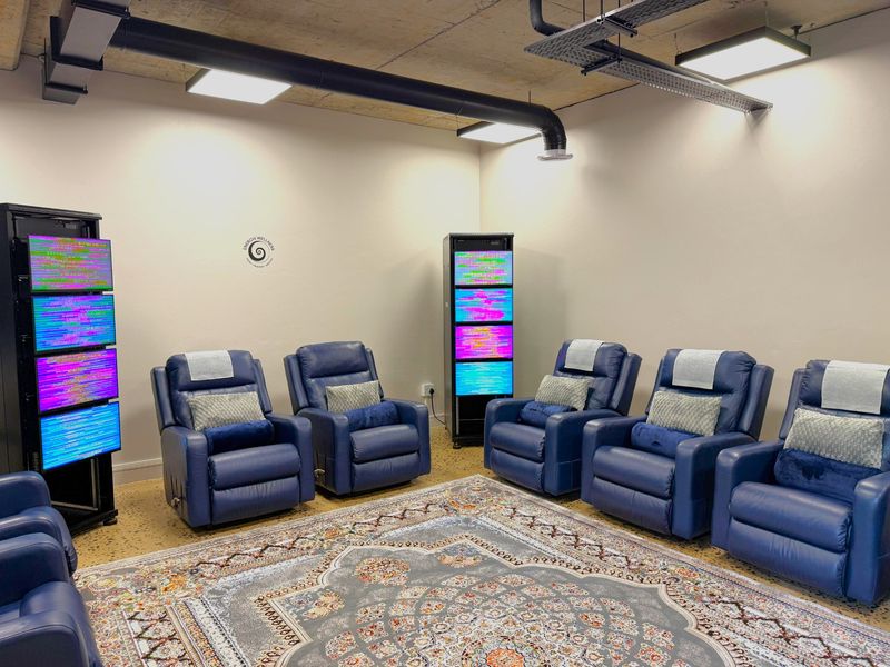 Modern office space featuring exposed concrete ceilings, industrial ducting, suspended LED lighting, and durable terrazzo flooring.