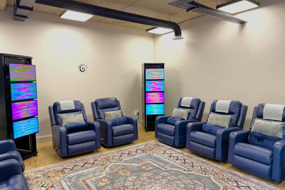 Modern office space featuring exposed concrete ceilings, industrial ducting, suspended LED lighting, and durable terrazzo flooring.