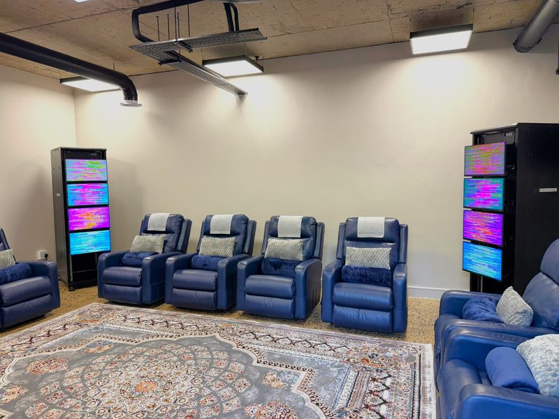 A modern office space featuring an industrial-style exposed concrete ceiling with integrated ducting, cable management systems, and professional lighting fixtures.