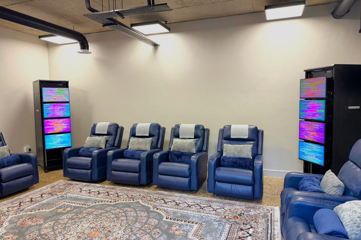 A modern office space featuring an industrial-style exposed concrete ceiling with integrated ducting, cable management systems, and professional lighting fixtures.