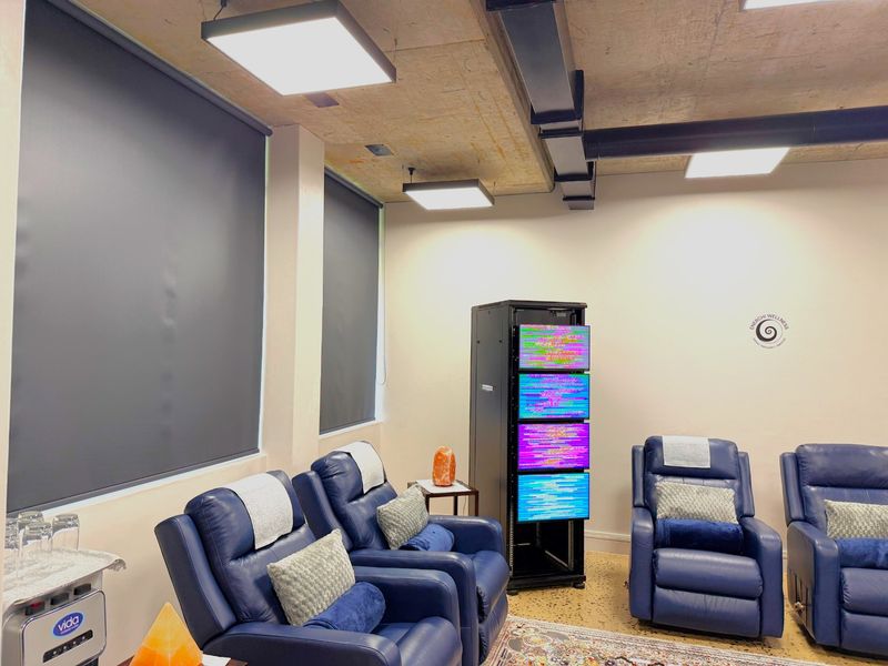 Modern office space featuring an exposed concrete ceiling with industrial ductwork, recessed LED lighting, roller blinds, and durable terrazzo flooring.