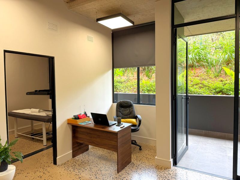 Modern office space featuring polished terrazzo flooring, exposed concrete ceiling, and direct access to a private balcony through black-framed glass doors.