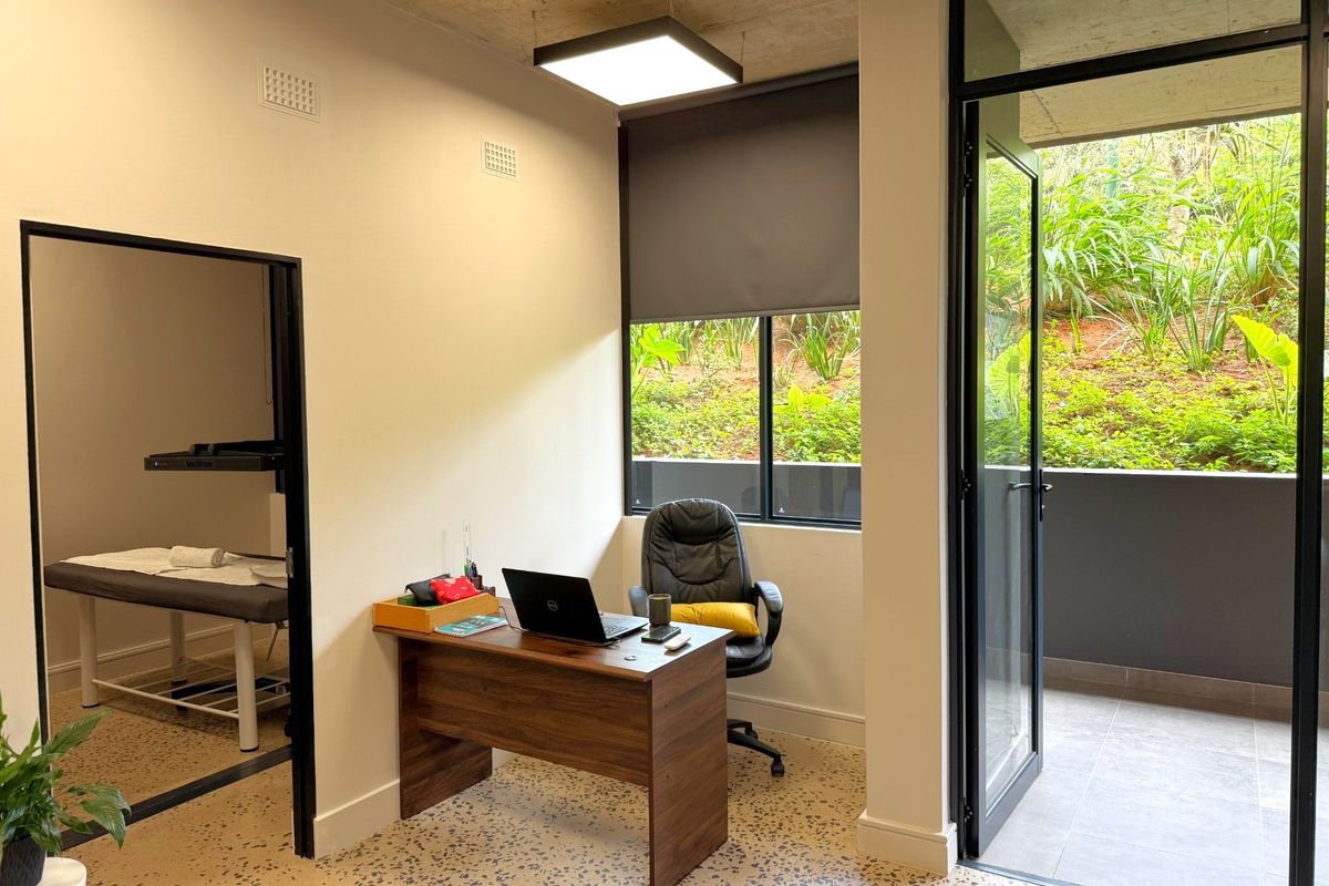 Modern office space featuring polished terrazzo flooring, exposed concrete ceiling, and direct access to a private balcony through black-framed glass doors.