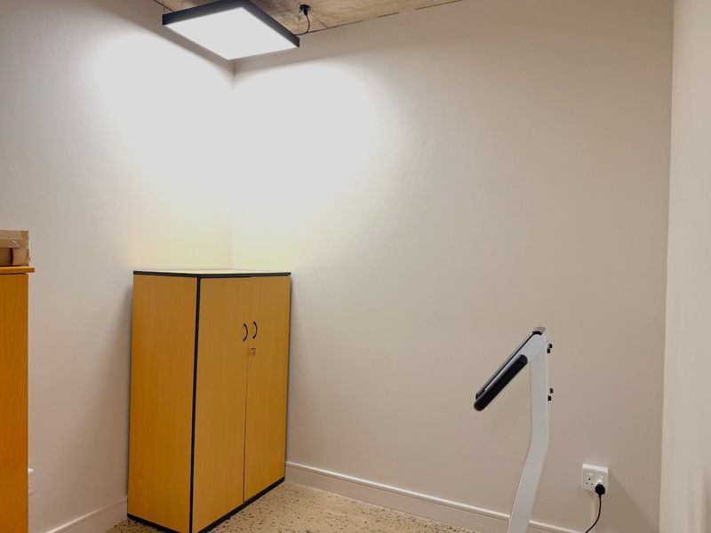 A functional office space featuring an exposed concrete ceiling, terrazzo flooring, and neutral wall finishes, providing a clean and professional work environment.