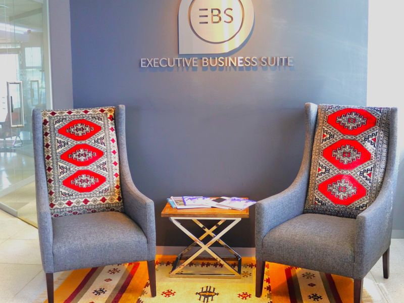 A professional office reception area featuring branded wall signage and a modern glass partition.