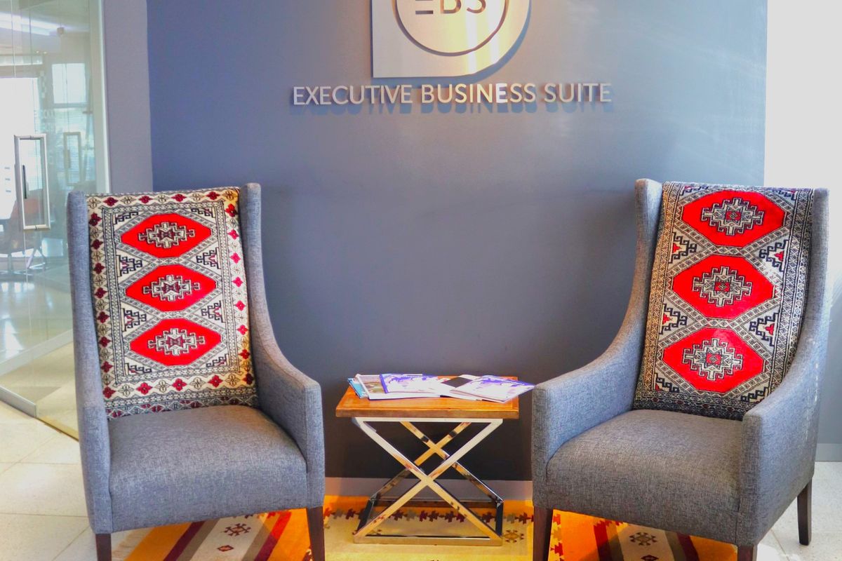 A professional office reception area featuring branded wall signage and a modern glass partition.