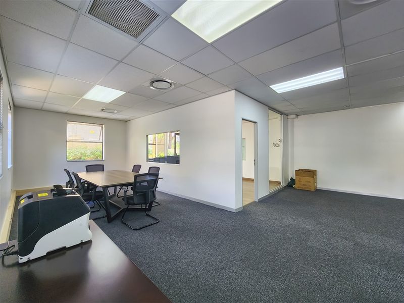 A functional office space featuring a suspended ceiling with recessed lighting, carpeted flooring, and an internal glass partition for a professional work environment.