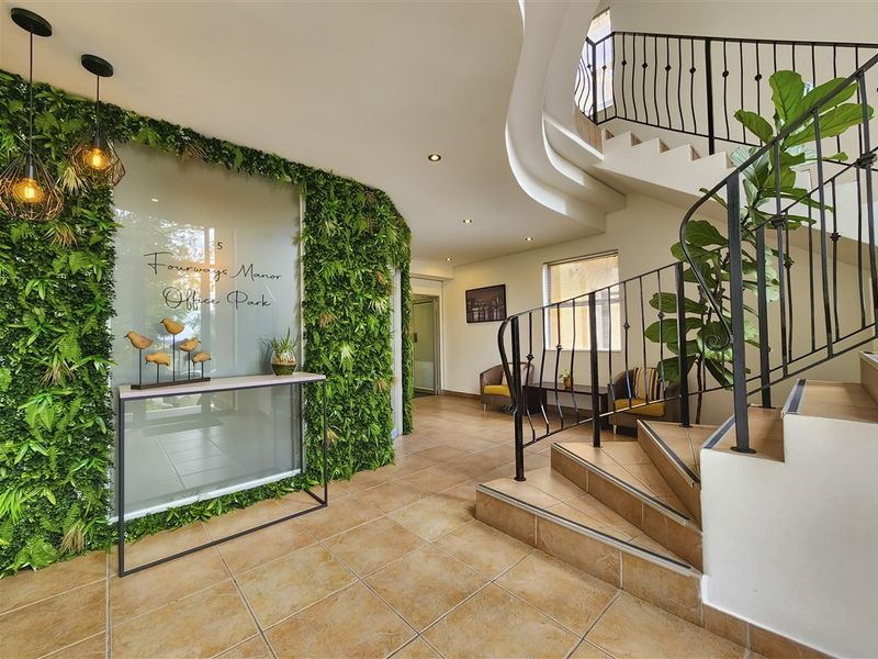 Welcoming office park entrance featuring a striking vertical garden wall, tiled flooring, and an elegant curved staircase with wrought iron railings.
