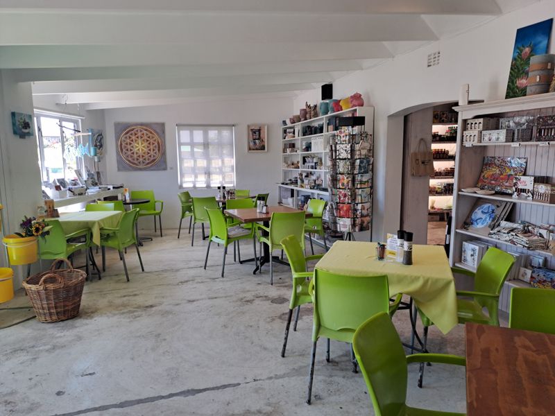 Open-plan commercial dining area featuring exposed ceiling beams, concrete flooring, and built-in display shelving, offering a casual and versatile layout.
