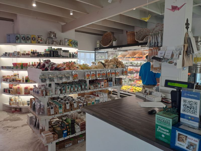 A retail shop interior featuring built-in display shelving, refrigerated cabinets, and a service counter with exposed ceiling beams and track lighting.