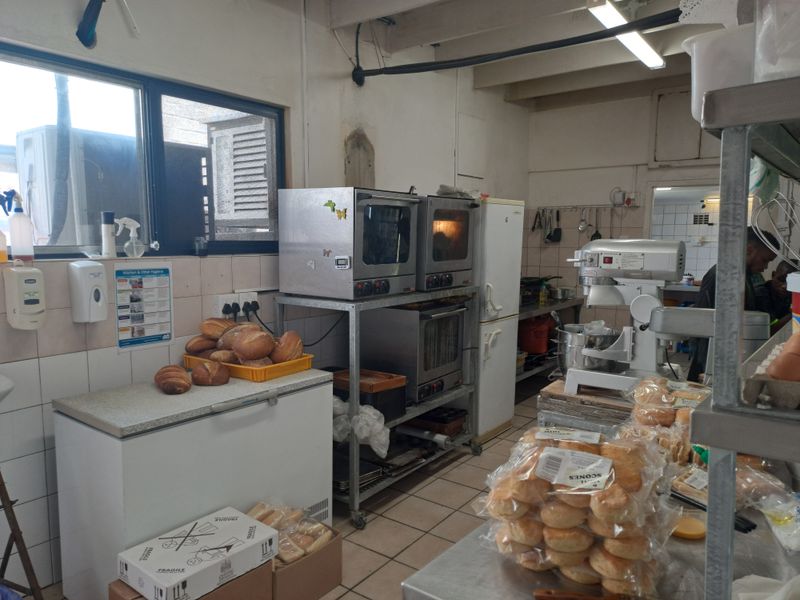 A functional commercial kitchen space featuring tiled surfaces, stainless steel shelving, and built-in commercial oven units, suitable for high-volume food preparation.
