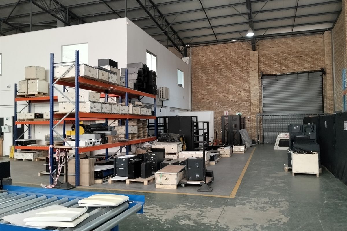 Spacious industrial warehouse unit featuring high ceilings with exposed steel trusses, roller shutter access, and durable concrete flooring.
