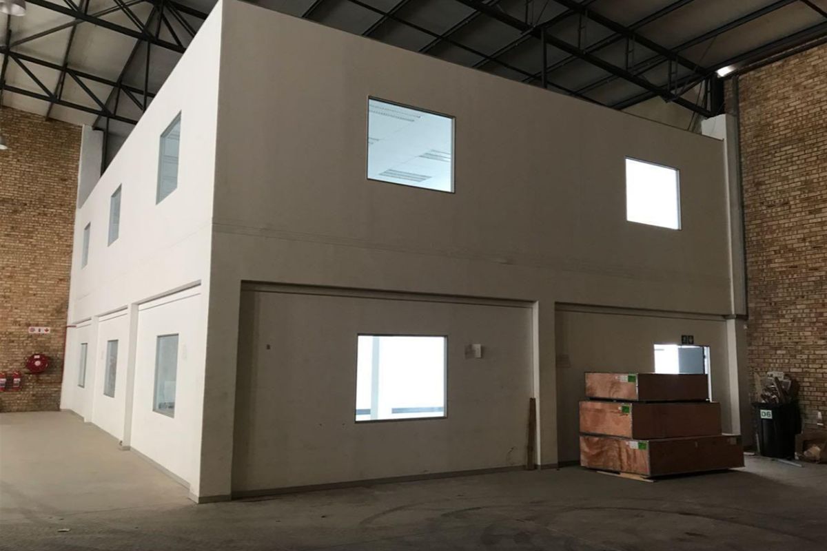 A spacious industrial warehouse featuring a double-story internal office block, exposed steel roof trusses, and durable concrete flooring.