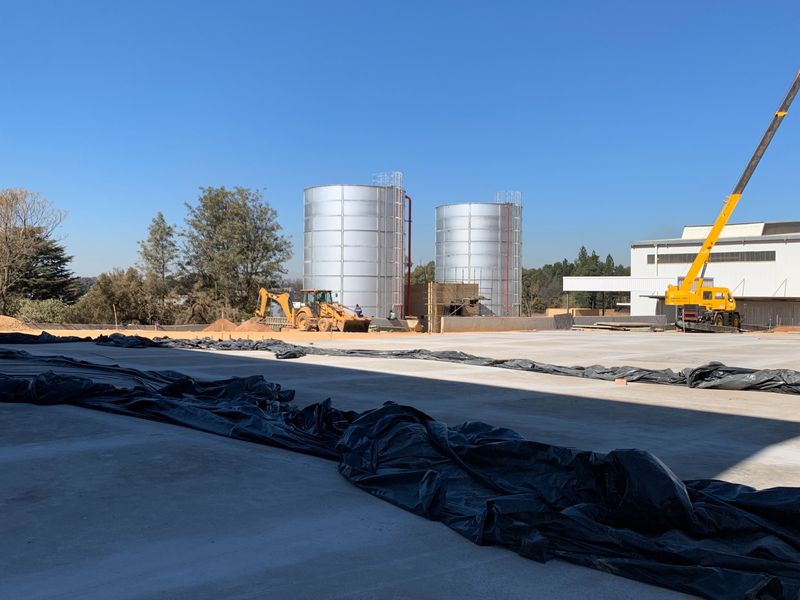 Industrial property exterior featuring large metal storage tanks and a expansive concrete yard currently under construction.