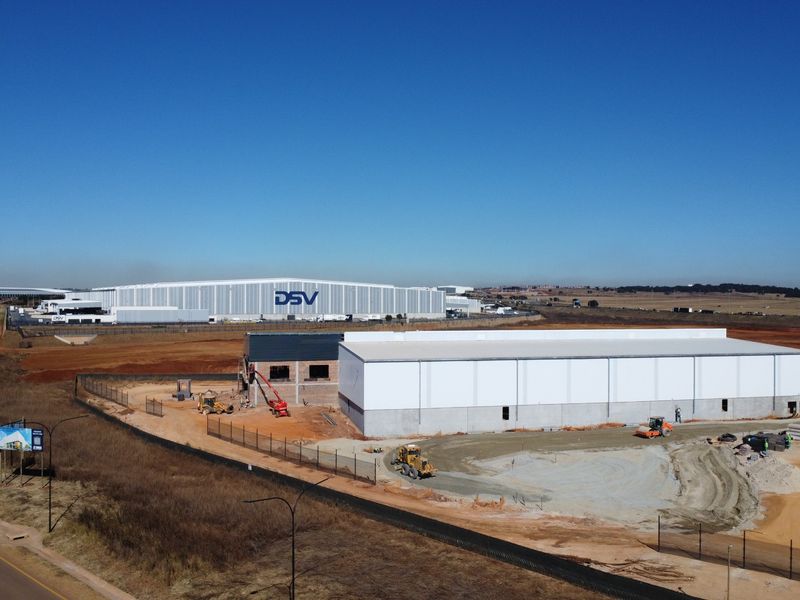 Aerial view of an industrial development site under construction, featuring large warehouse structures and ongoing site preparation work.