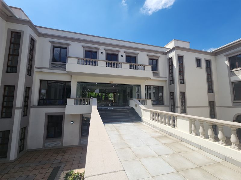 A well-maintained multi-story office building facade featuring a prominent stone staircase, balustrades, and a modern glass entrance.