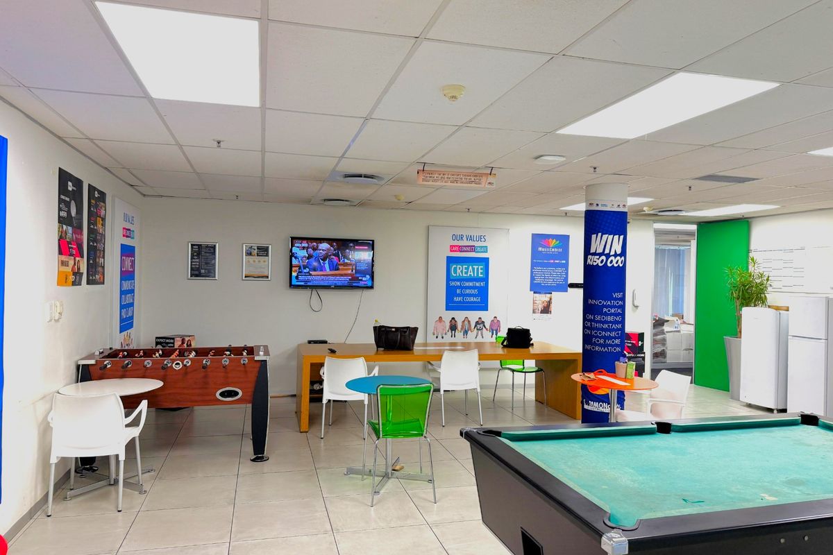 A spacious office breakout area featuring tiled flooring, suspended ceiling with recessed lighting, and integrated air conditioning vents.