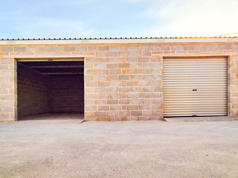 Industrial garage facility featuring concrete block construction, a secure roller shutter door, and an open bay for vehicle or storage access.