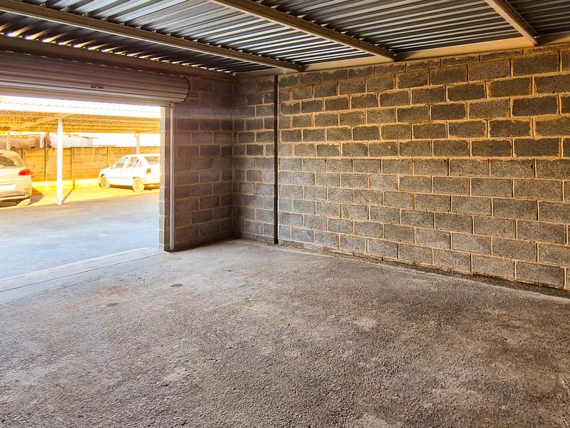 A spacious, empty industrial-style garage featuring exposed concrete block walls, a corrugated metal ceiling, and a functional roller shutter door.