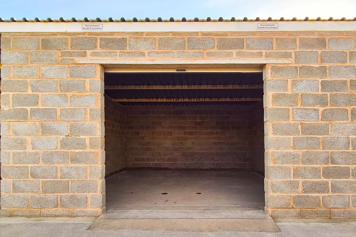 A functional industrial garage space featuring exposed concrete block walls, a corrugated metal roof, and a durable concrete floor.