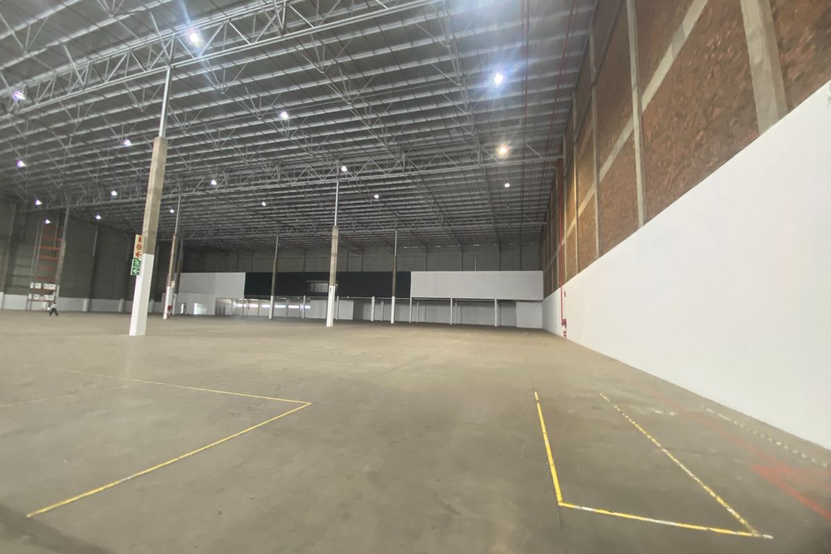 Spacious industrial warehouse featuring high ceilings with exposed steel trusses, polished concrete flooring, and integrated fire safety systems.