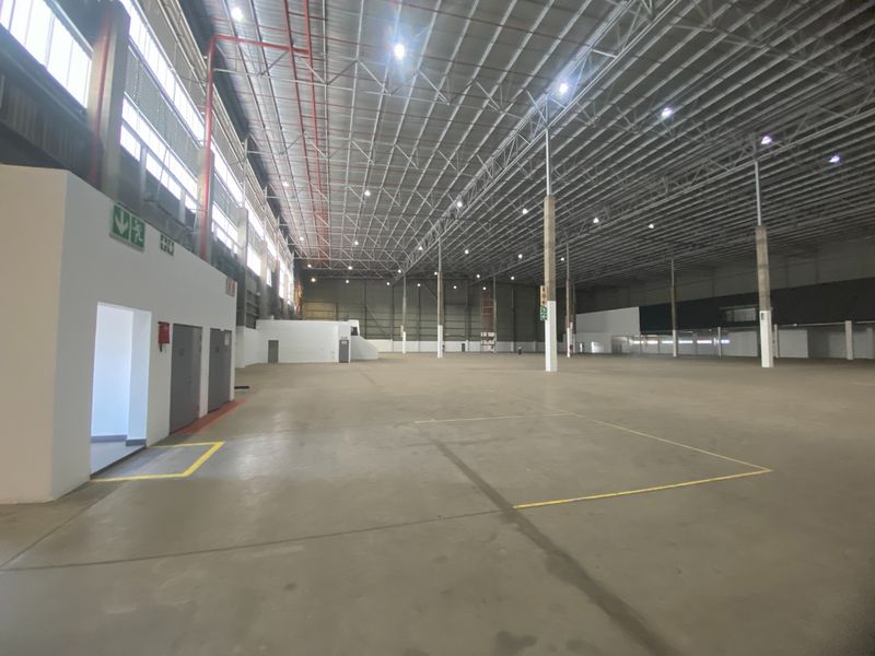 Spacious industrial warehouse featuring high-clearance ceilings, exposed steel trusses, polished concrete flooring, and integrated fire safety systems.