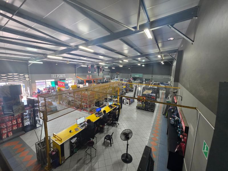 High-angle view of a commercial retail space featuring exposed steel roof trusses, tiled flooring, and integrated service counters.