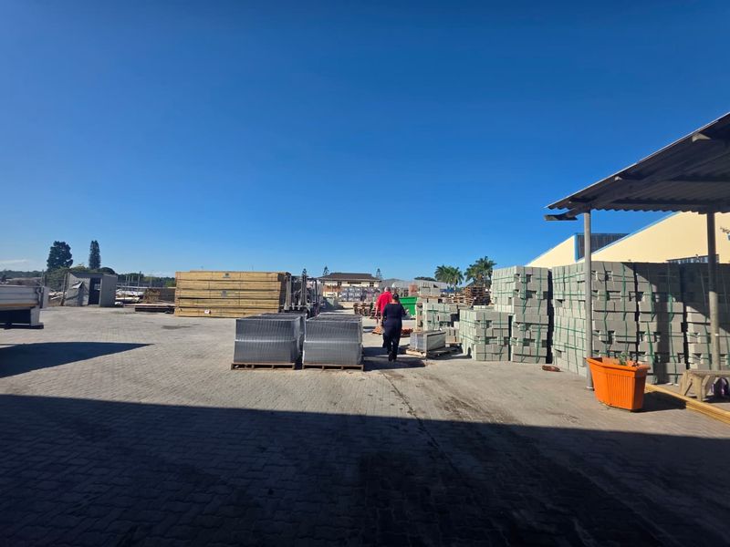 A spacious commercial paved yard featuring a covered loading area and ample storage space for building materials.