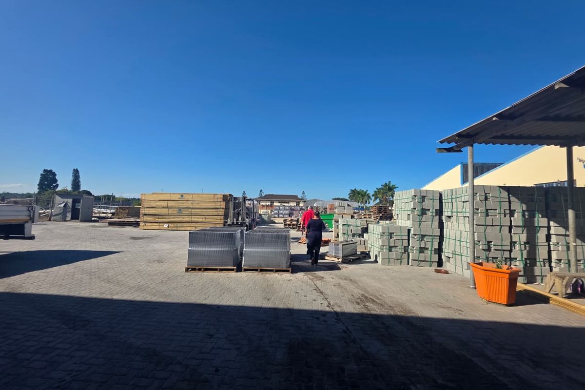 A spacious commercial paved yard featuring a covered loading area and ample storage space for building materials.