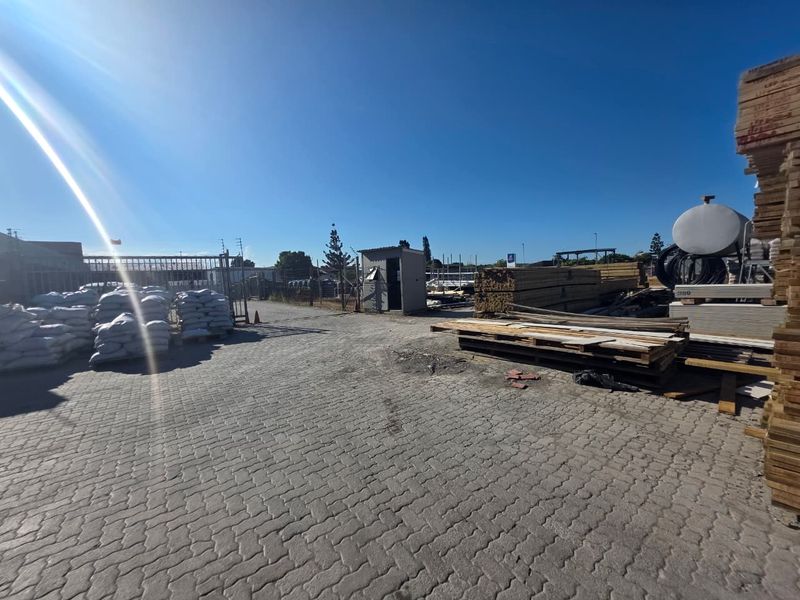 A spacious commercial yard featuring paved ground, security fencing, and a small utility structure, suitable for storage or industrial operations.