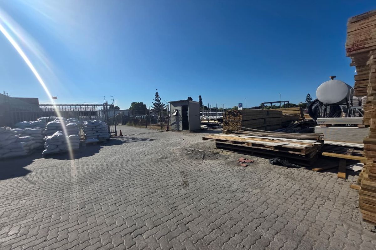 A spacious commercial yard featuring paved ground, security fencing, and a small utility structure, suitable for storage or industrial operations.
