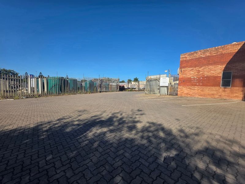 Commercial property exterior featuring a paved parking area, brick facade, and secure perimeter fencing with electric security measures.