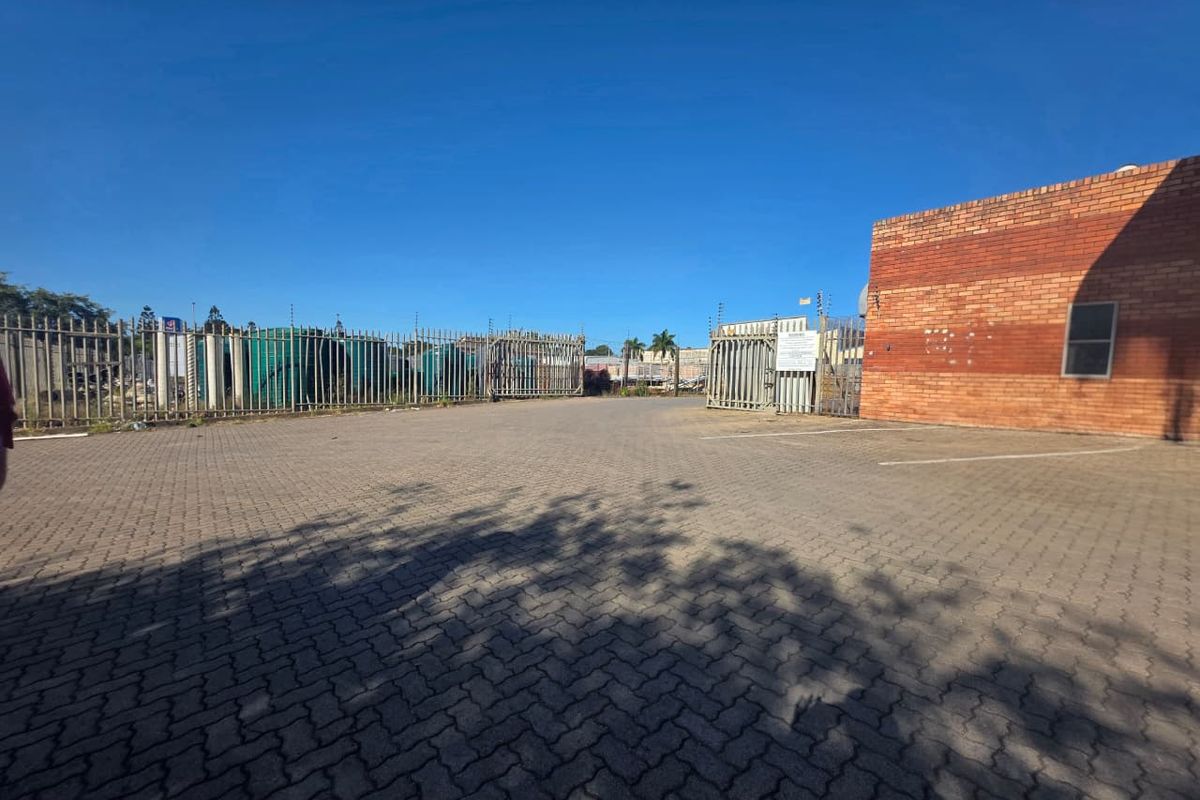 Commercial property exterior featuring a paved parking area, brick facade, and secure perimeter fencing with electric security measures.