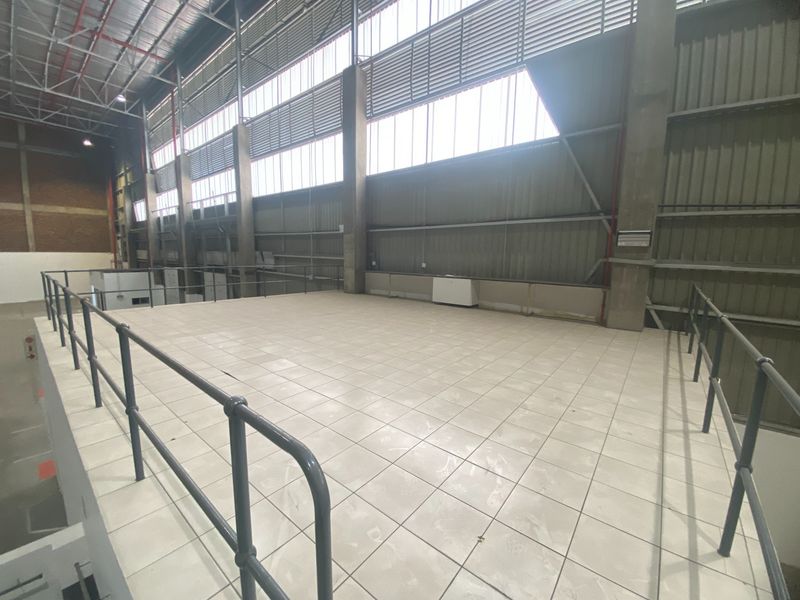 Spacious industrial mezzanine level featuring tiled flooring, metal safety railings, and high-level louvered windows, suitable for storage or office conversion.