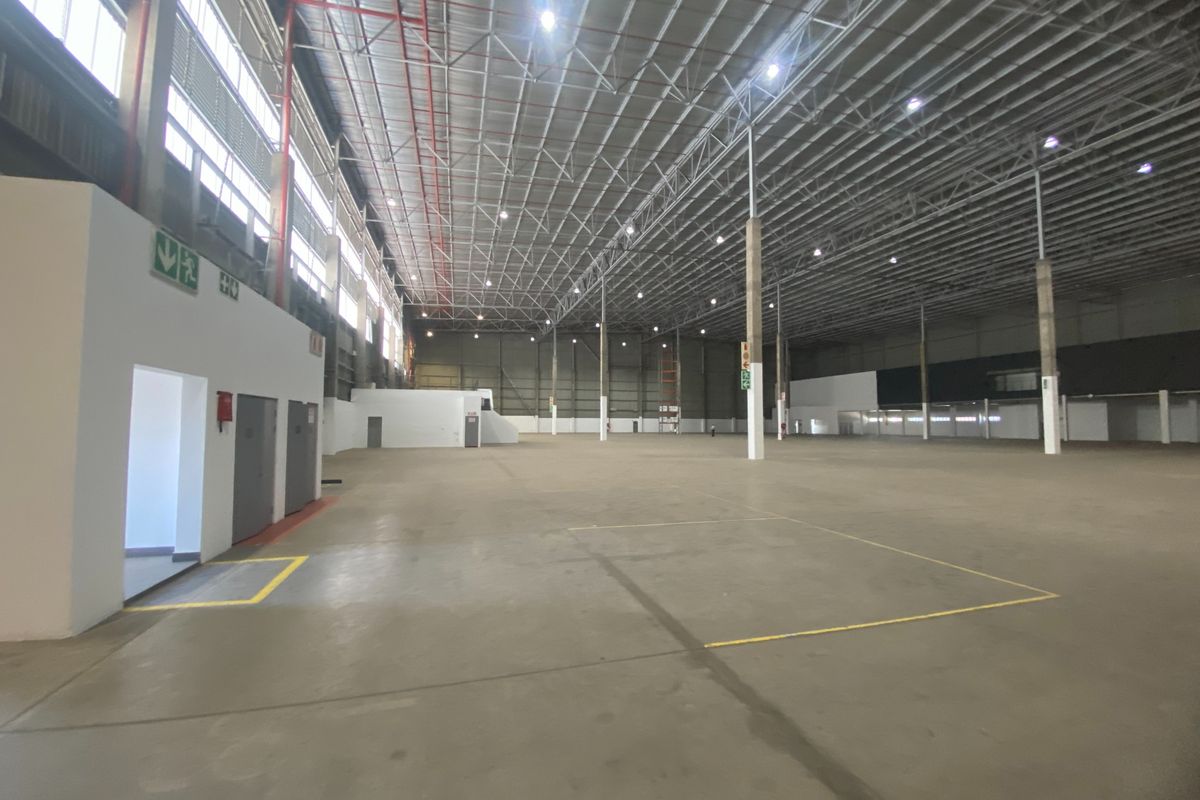 Spacious industrial warehouse featuring high-clearance ceilings, exposed steel trusses, polished concrete flooring, and integrated fire safety systems.
