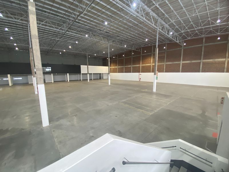 Spacious industrial warehouse featuring high ceilings with exposed steel trusses, concrete flooring, and ample open floor space suitable for various commercial or storage operations.