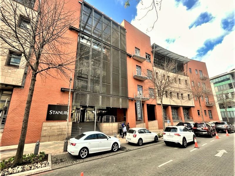 Front elevation of a multi-story commercial office building featuring a brick facade, glass curtain walling, and integrated metal screening elements.